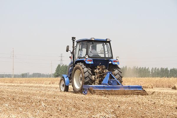 合作社拖拉机正在对土地进行旋耕作业.jpg